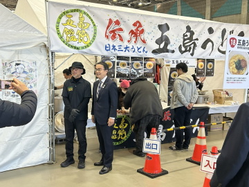 知事がブースの前に立っている